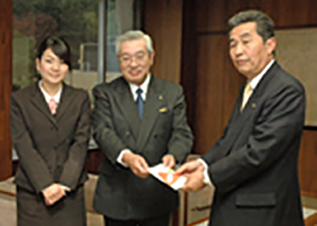 鈴木東海市長（右）に募金を手渡す吹奏楽団代表